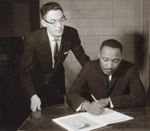 Photo: Jim Ehrman stands behind Martin Luther King, who is writing on a book or pamphlet