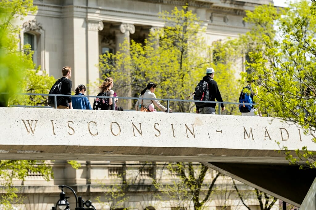 Photo: Students walking across pedestrian bridge that says "Wisconsin-Madison"