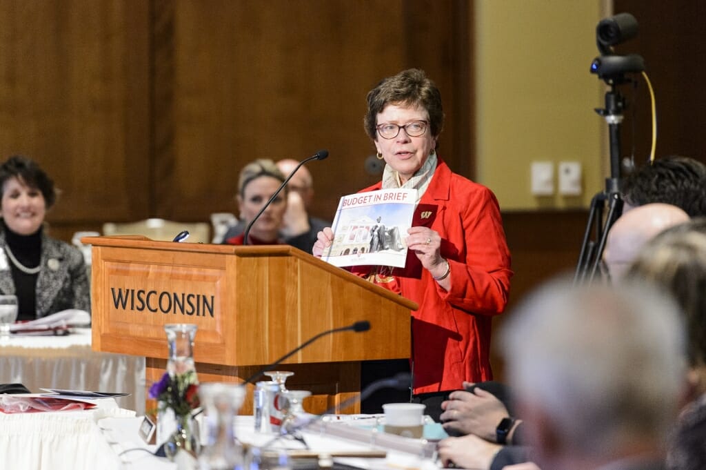 Photo: Rebecca Blank holding up budget booklet at podium