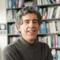 Photo: Richard Davidson, arms folded, in front of bookshelf