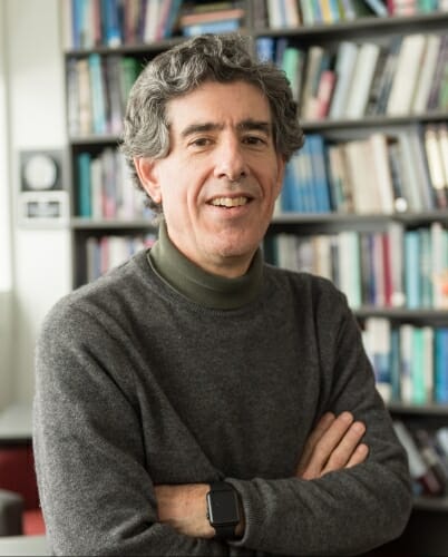 Photo: Richard Davidson, arms crossed, in front of bookshelf