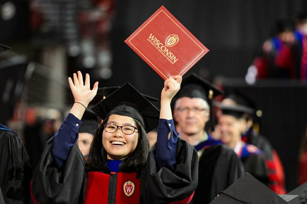 Photo: Doctoral graduate holding up hands with diploma cover