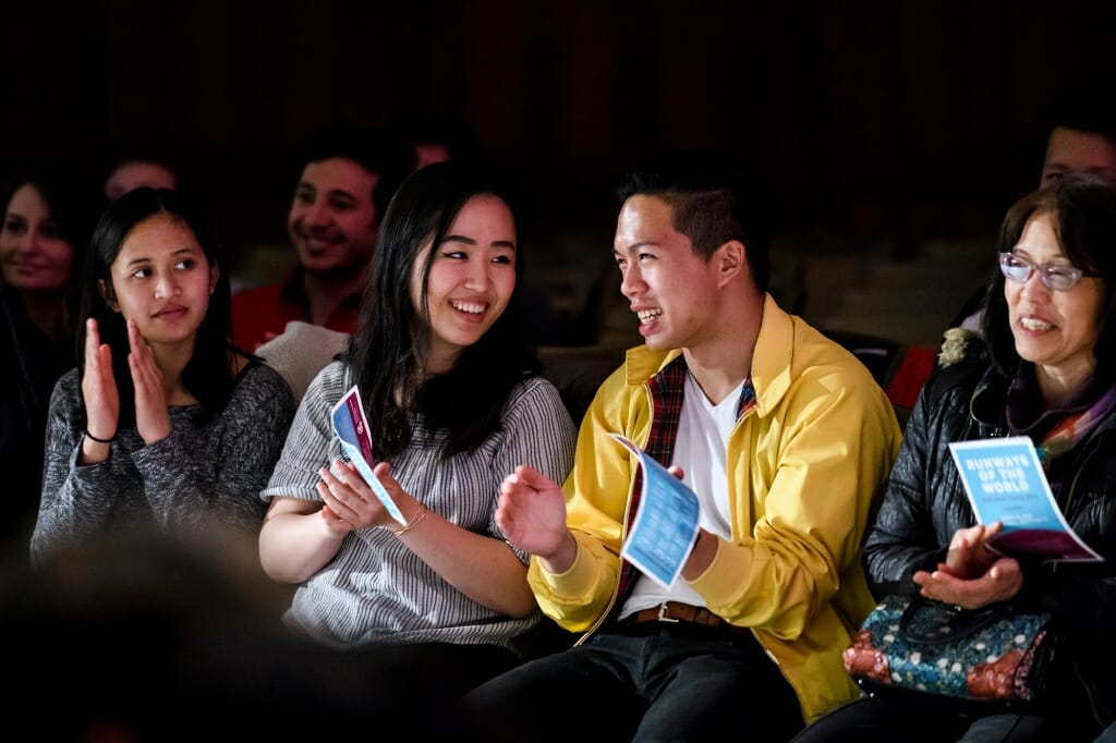 Audience members applaud as students model clothing from around the world.