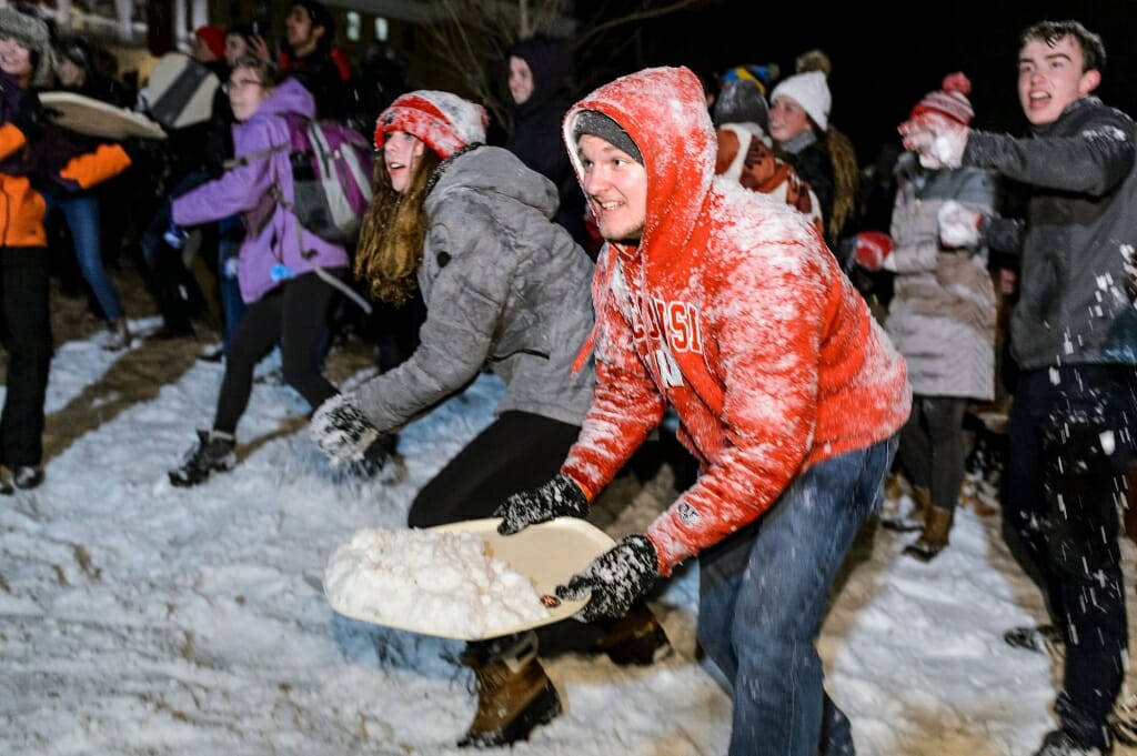 Photo of student scooping snow with a tray.