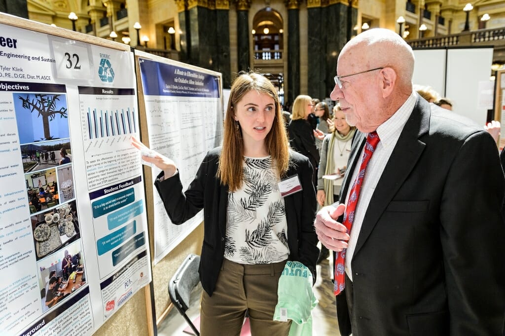 Sen. Fred Risser listens to UW-Madison student Morgan Sanger talk about her and her teammates' research project.