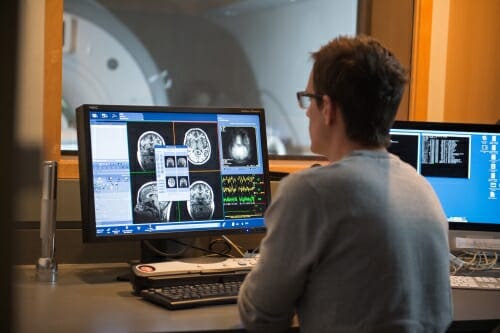 Photo: Unidentified researcher looking at brain scan images on computer screen