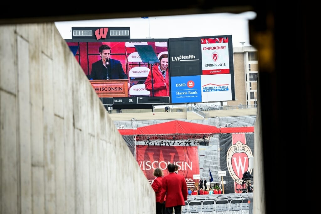 Photo of ABC News anchor David Muir rehearsing at the podium for his role as the keynote speaker of Saturday's ceremony at Camp Randall.