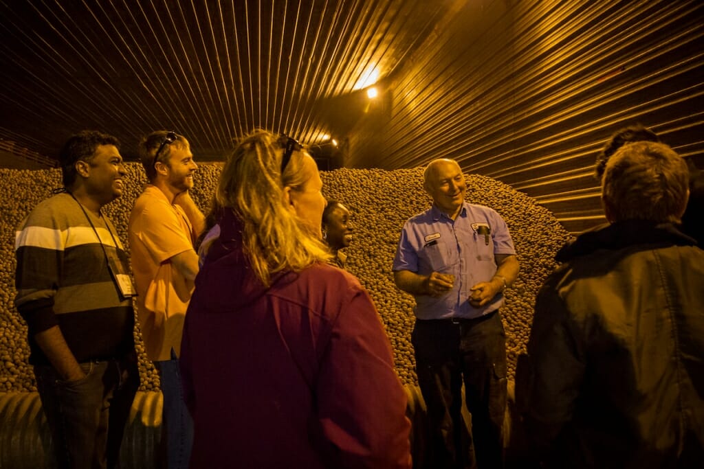 Photo: Farmer standing with group in front of potato pile