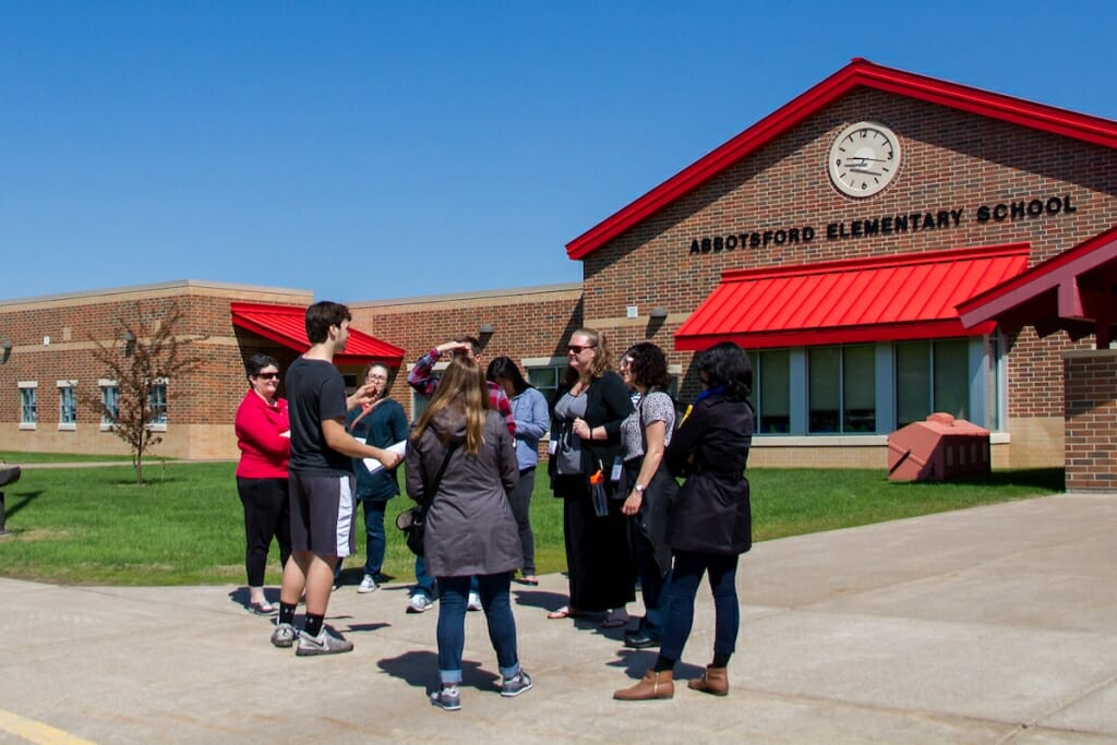 Photo: Student with visitors outside school building