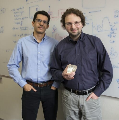 Photo: Kats and Jad Salmon standing in front of a whiteboard with graphs and equations