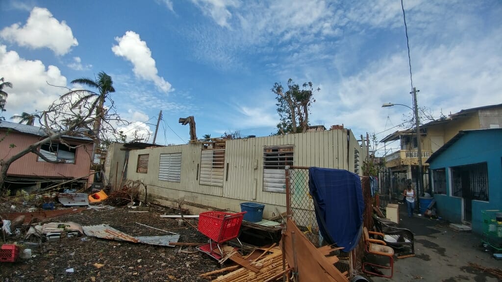 Photo: Structure with roof missing and debris in yard