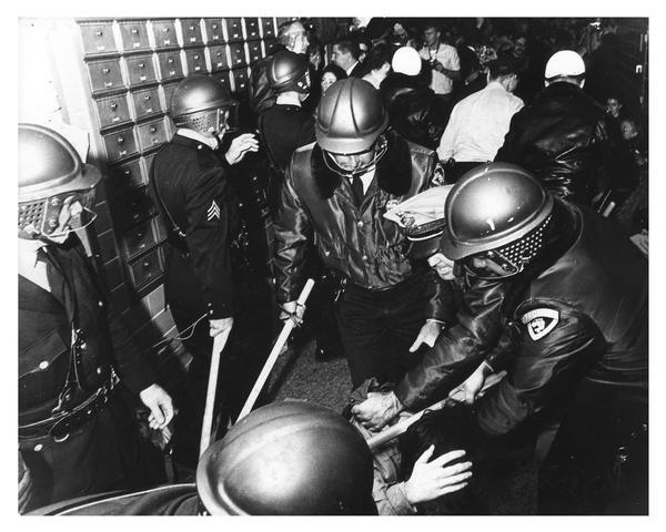 University of Wisconsin–Madison students clash with riot police during campus demonstration to protest Dow Chemical involvement in the Vietnam conflict. Here, several police officers with clubs hold a student down on the floor.