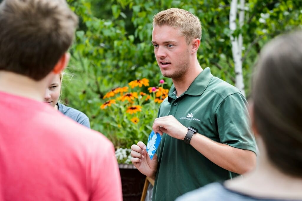 Staff member Kolin Goldschmidt helps visitors make decorative sun prints.