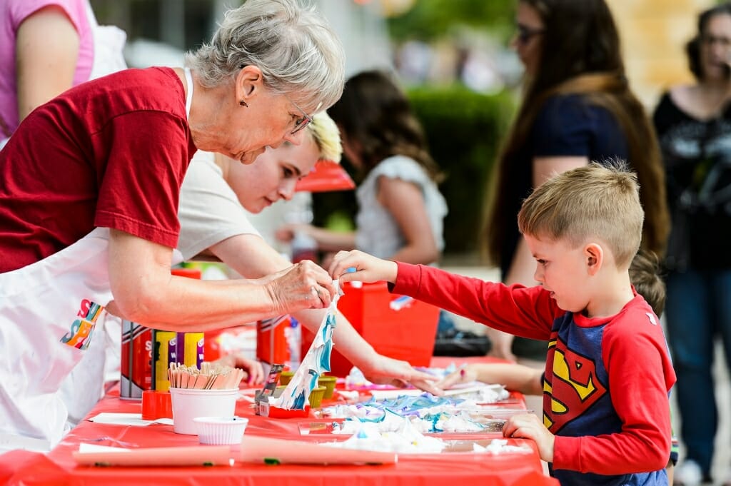 Volunteer docent Mary Teselle, left, helps participant Lev Stolz-Greenberg, 5, reveal a print.