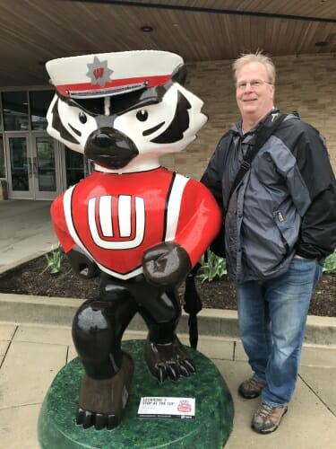 Photo: Helmkamp standing outside next to Bucky statue painted as UW Band member