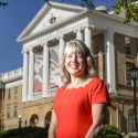 Photo: Lori Reesor standing in front of Bascom Hall pillars with Bucky Banner