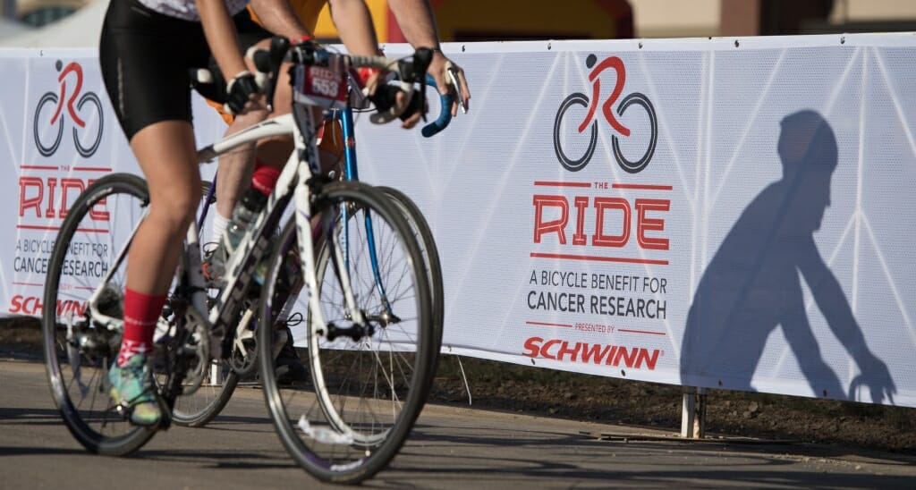 Photo: Bike riders silhouetted against white sign