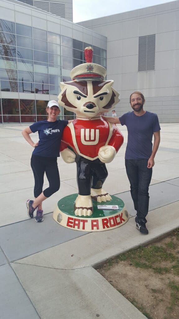 Artist Jill Iwanski and her boyfriend Jake Ghilardi stand next to "...And On Wisconsin!" which Iwanski created for Bucky on Parade. The public art project saw local artists from across the state design 85 unique interpretations on Bucky Badger.