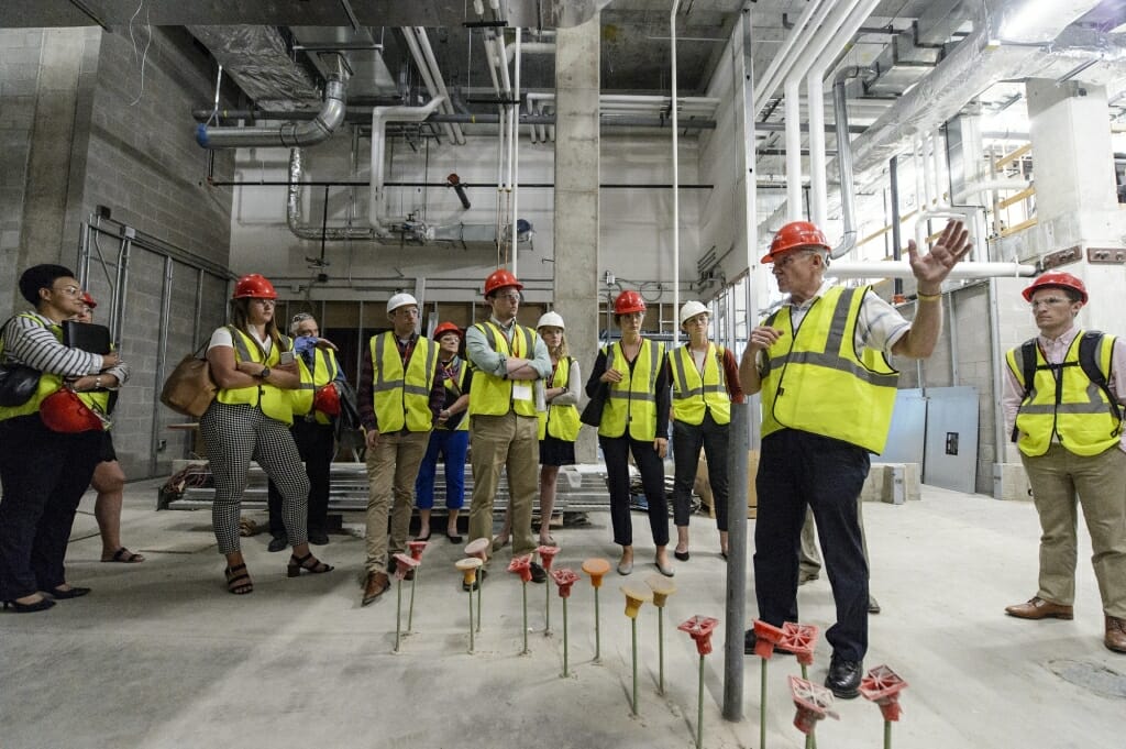 Photo: People in neon yellow vests and hardhats standing in unfinished building