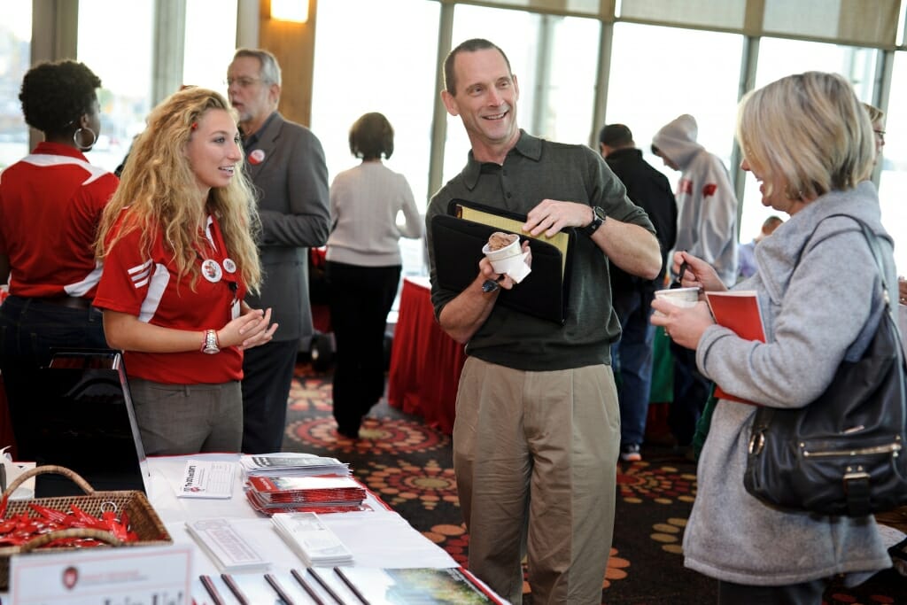 Photo: Conference volunteer talking with attendees at table