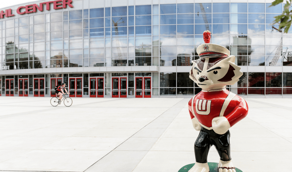 "...And On Wisconsin!" stands outside of the Kohl Center. The Bucky statue is dressed in UW Marching Band attire and is doing the signature marching step of the band. 