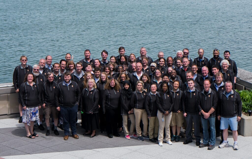 Photo: Large group of employees standing with lake in background