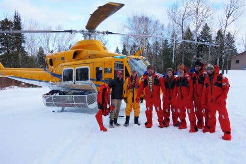 Photo: People in jumpsuits standing in front of helicopter in the snow