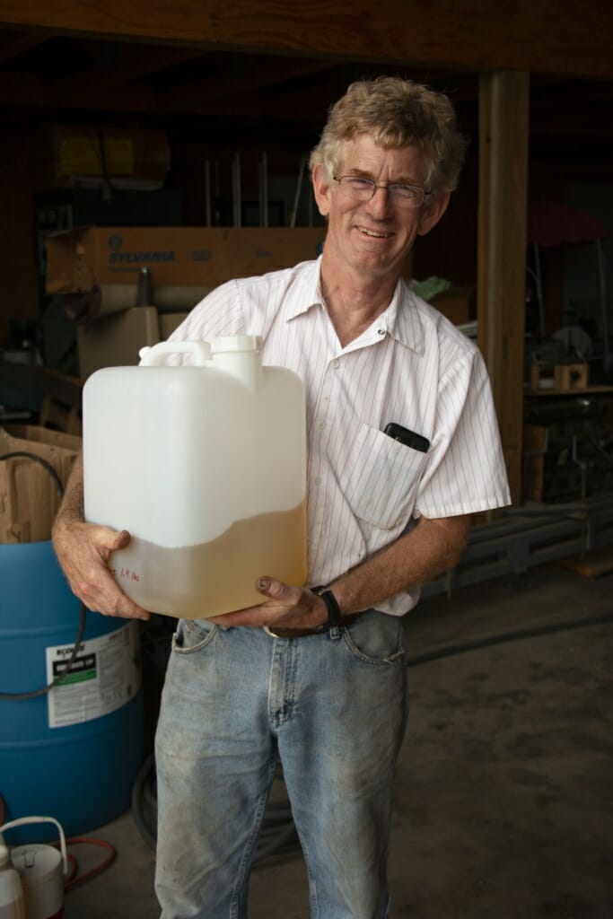 Man holding square plastic container of mint exract.