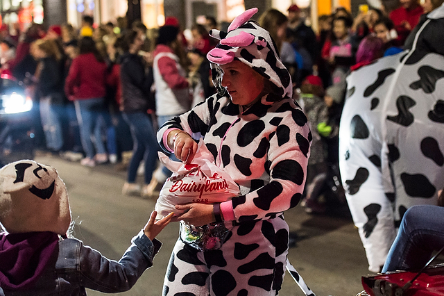 Dressed in a cow suit, a woman with the Badger Dairy Club hands out candy to children during the parade on State Street.