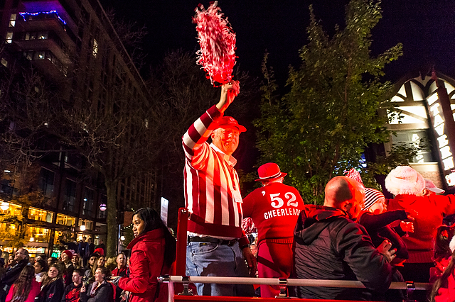 Alumni riding on the Bucky Wagon wave to the crowd.