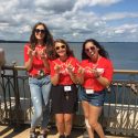 A photo of three college students holding their hands in the shape of a 