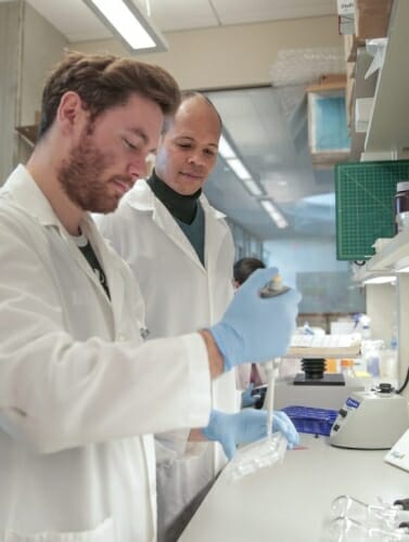 Photo: Randolph Ashton and a researcher in lab wearing white lab coats