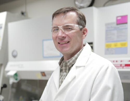 Photo: Sean Palecek in a lab wearing safety goggles and a white lab coat