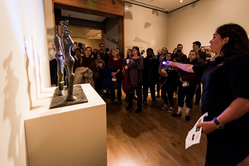 Tour guide Elizabeth Quirmbach uses a flashlight to show guests artwork.