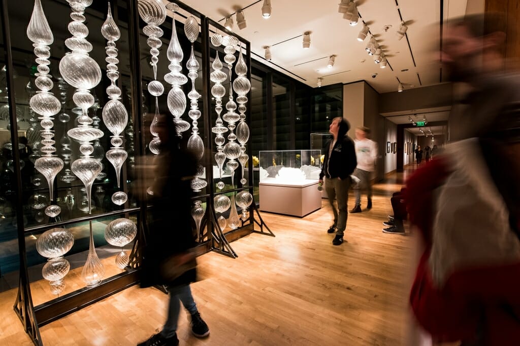 Guests look at a glass screen created by the artist Andy Paiko at the Chazen.