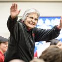 Ada Deer raises her hands in greeting to the students.