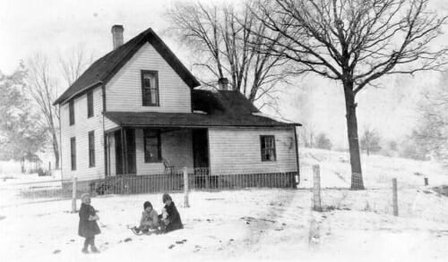 Black and white photo of Signe with her sisters in the snow in front of the family farmhouse.