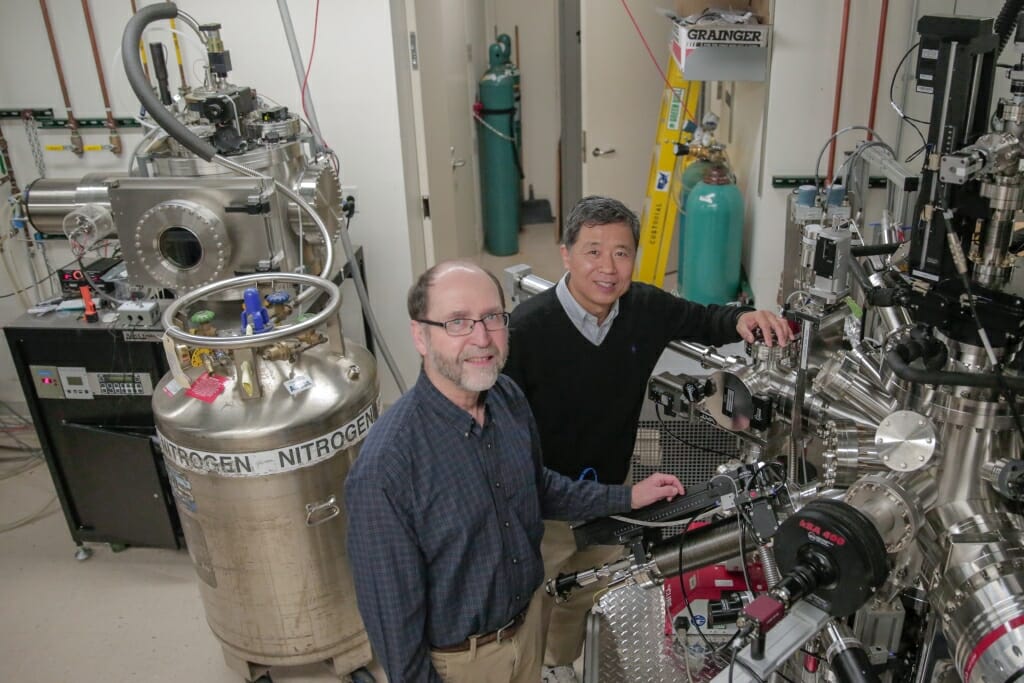 Photo: Chang-Beom Eom, right, and Mark Rzchowski inspect a materials growth chamber.