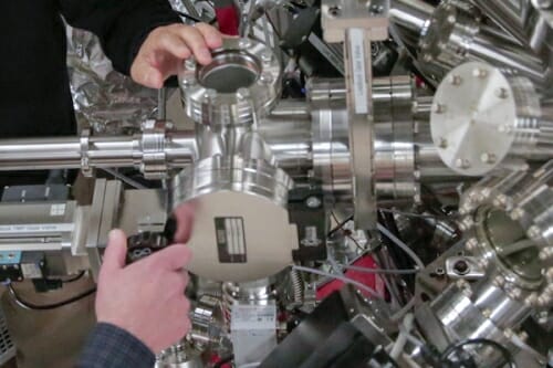 Photo: Closeup of hands pointing to materials growth chamber