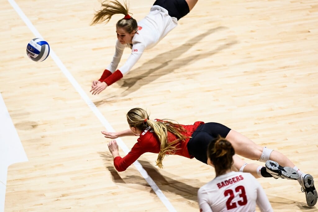 Two Wisconsin players simultaneously dive for a ball.