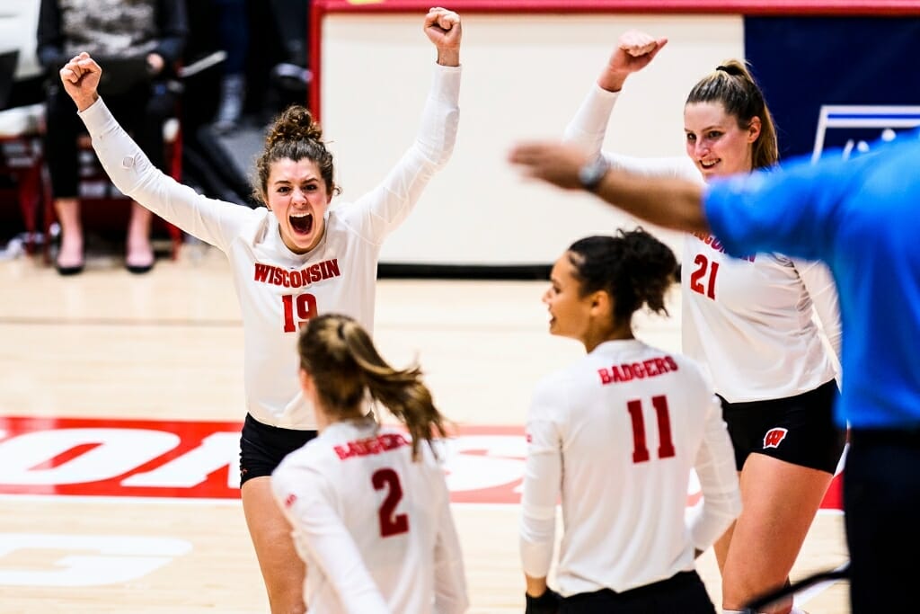 M.E. Dodge, wearing No. 19, lifts her arms in celebration as other players look on in jubilation after a good point.