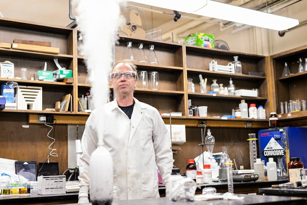 Photo: Man next to bottle with vapor shooting out the top