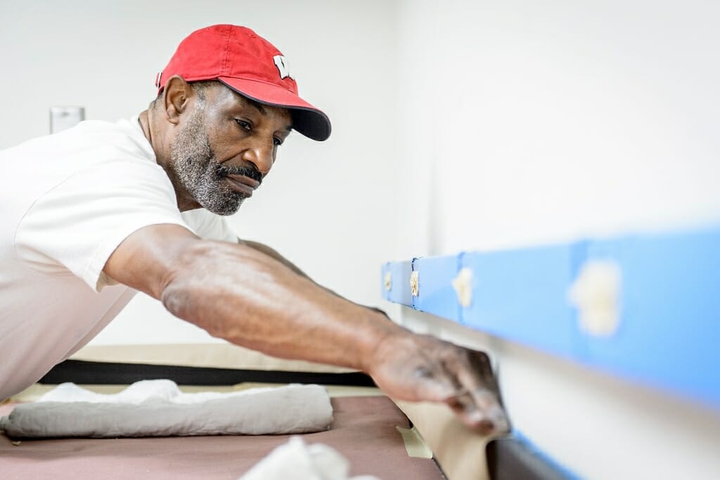 Photo: Man applying painter's tape to a wall