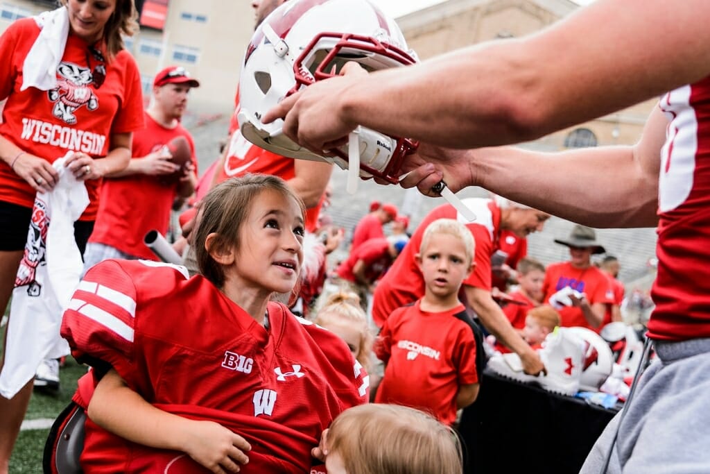 Photo: Football player placing helmet on girl's head