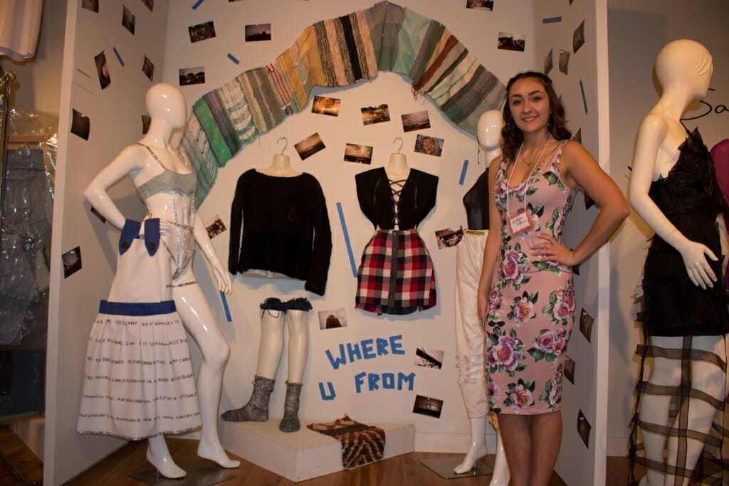 Photo: A woman with her dresses and other garb that she designed.