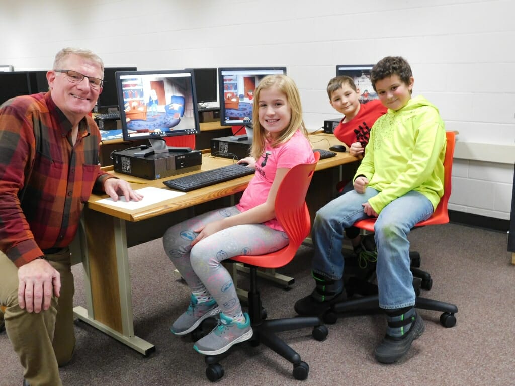 A teacher poses for a photo with three students.