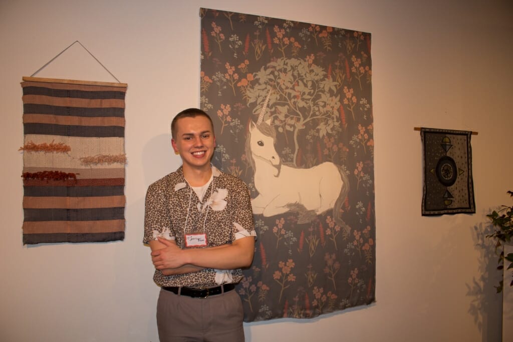 A man with some wall hangings he designed.