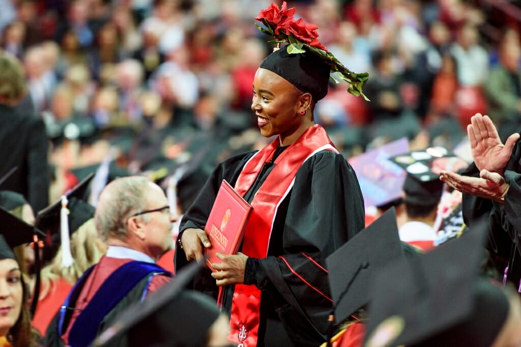 Photo of a graduate with an elaborately decorated floral mortarboard.