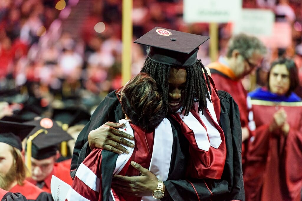 Photo of a graduate sharing a hug before the ceremony.