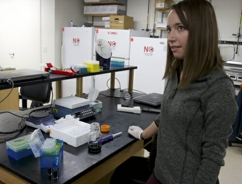 Photo: Student standing next to lab bench